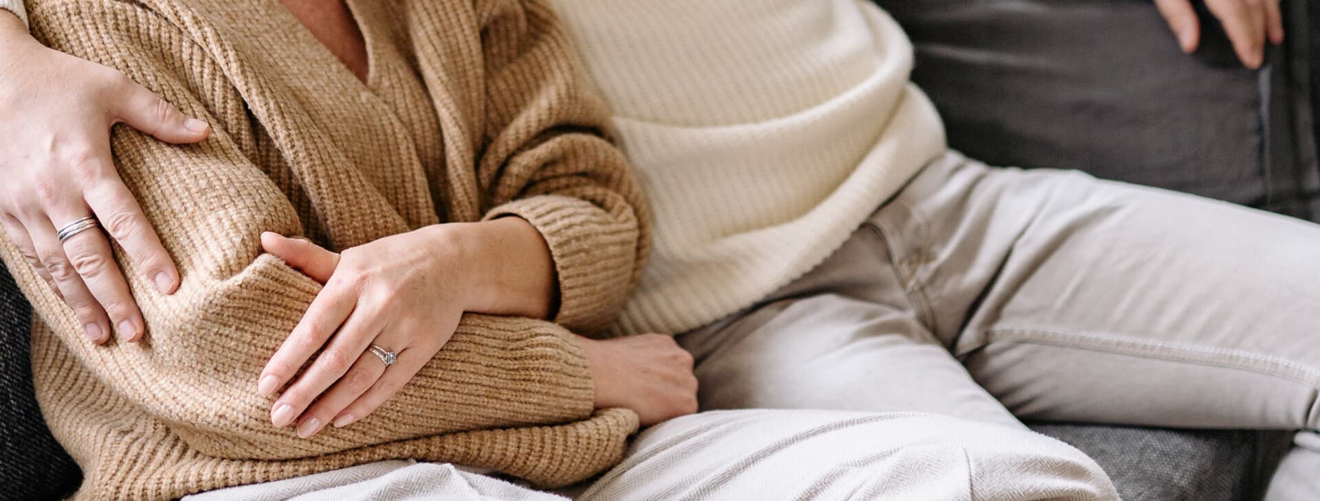 Två personer sitter i en soffa och håller om varandra