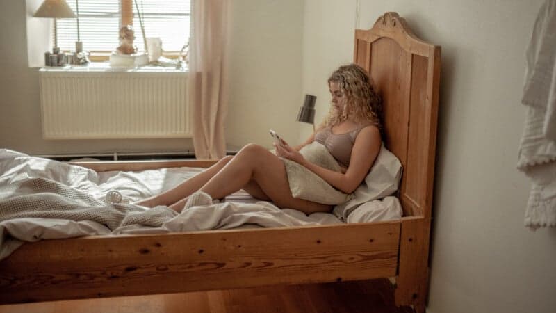 Kvinna sitter i säng. Kvinna sitter i säng.