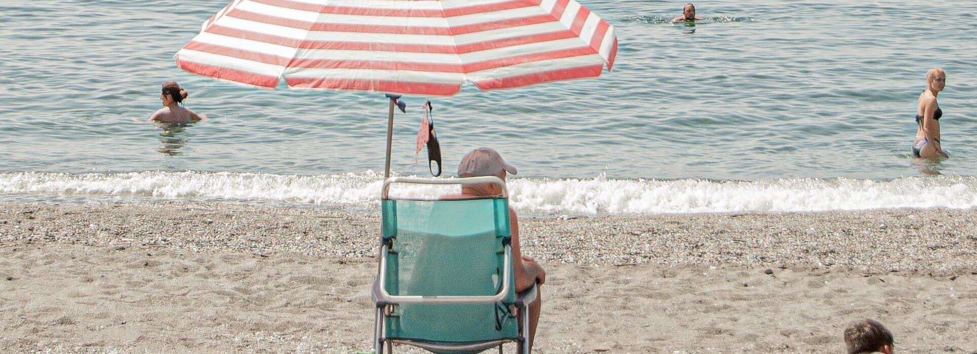 man på strand under parasoll