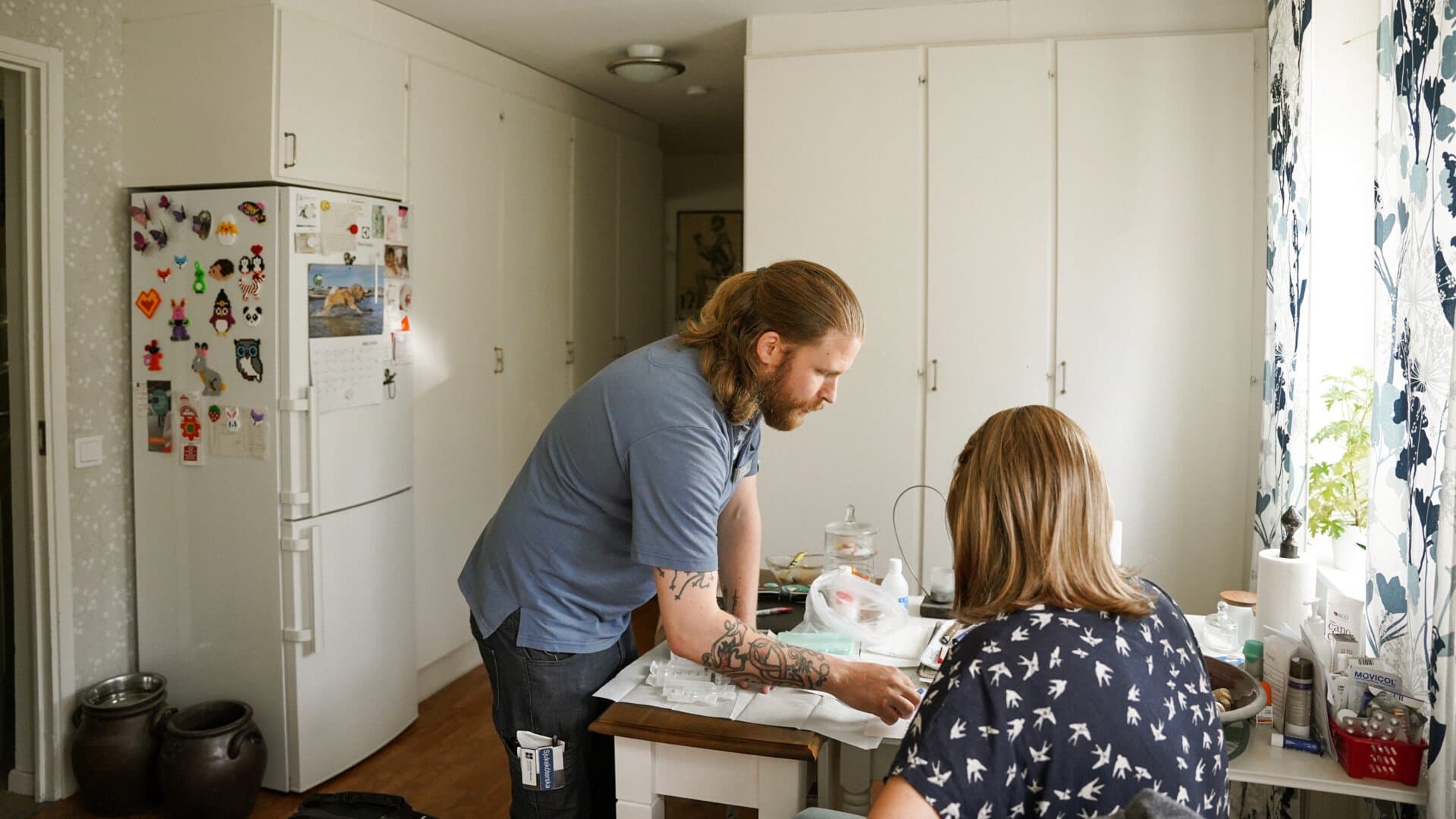 Sjuksköterska hjälper patient i hemmet med att lägga om sår